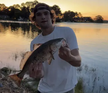 Guy holding up a fish he caught at the lake
